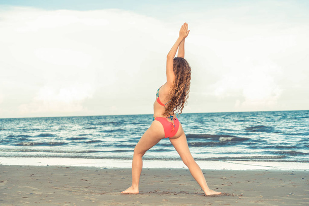 Молодая женщина практикует позу йоги на пляже летом. Здоровый образ жизни и медитация
. - Фото, изображение
