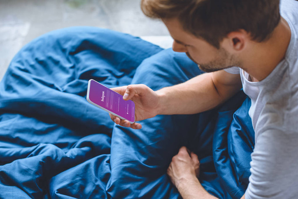 selective focus of young man in bed using smartphone with instagram on screen  - Фото, зображення