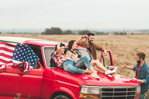 group of young american car travellers relaxing in flower field - Photo, Image