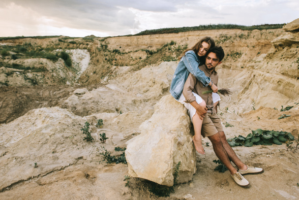 young beautiful couple embracing and sitting on rock in canyon - Foto, Imagem
