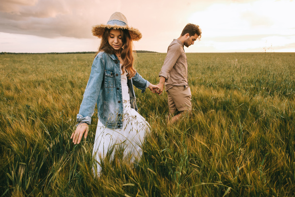 stylish couple holding hands and walking on green meadow - Photo, Image