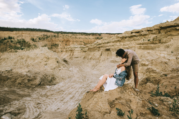 стильный мужчина обнимает и целует девушку в песчаном каньоне
 - Фото, изображение