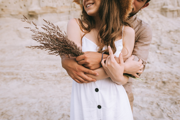 cropped view of stylish boyfriend hugging his girlfriend with floral bouquet - Foto, immagini