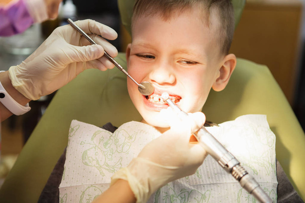 Ein kleiner Junge beim Empfang eines Zahnarztes in einer Zahnklinik. Kinderzahnheilkunde, Kinderzahnheilkunde. ein weiblicher Stomatologe - Foto, Bild