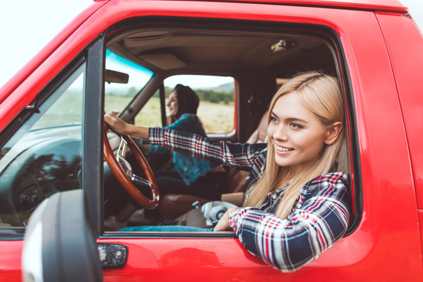 Widok z boku szczęśliwy młodych dziewczyn o podróż samochodem i jazda przez pola - Zdjęcie, obraz