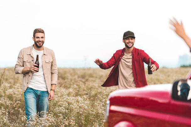 happy young men with beer running at car in field - Foto, imagen