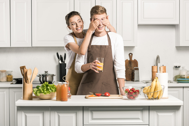 дівчина закриває очі для хлопця, коли він готує салат на кухні
 - Фото, зображення