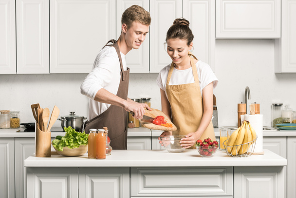 pareja joven cocinar ensalada y poner verduras saludables en un tazón en la cocina
  - Foto, Imagen