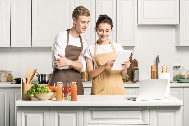 jovem casal olhando para tablet na cozinha
 - Foto, Imagem