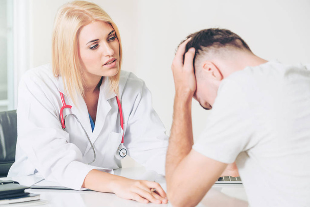 Femme médecin parle à un patient masculin sérieux dans le bureau de l'hôpital. Soins de santé et services médicaux
. - Photo, image