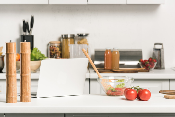 laptop e tigela para salada no balcão da cozinha na cozinha
 - Foto, Imagem