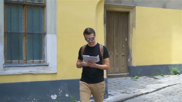 Man tourist with a city map and backpack in Europe street. Caucasian boy looking with map of European city. - Filmmaterial, Video