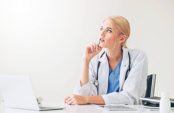 Женщина-врач в больнице или институте здравоохранения работает над медицинским отчетом за рабочим столом
. - Фото, изображение