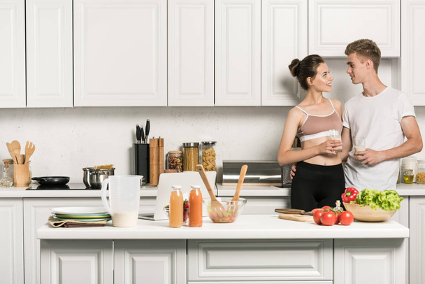 Genç çift sarılma ve birbirine mutfakta bakarak - Fotoğraf, Görsel