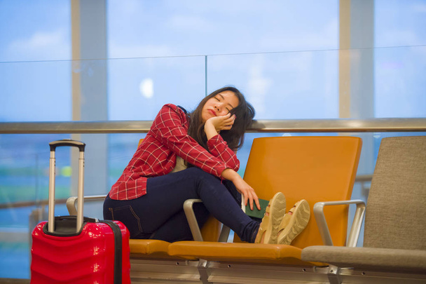 lifestyle portrait of young pretty tired and exhausted Asian Korean tourist woman in airport sleeping bored sitting at boarding gate hall waiting for delayed or canceled flight - Foto, afbeelding
