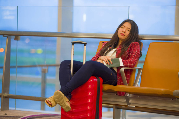 lifestyle portrait of young pretty tired and exhausted Asian Korean tourist woman in airport sleeping bored sitting at boarding gate hall waiting for delayed or canceled flight - Foto, imagen