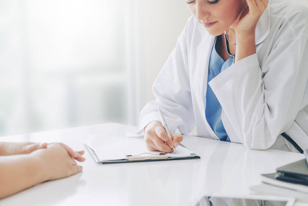 Ärztin spricht mit Patientin, während sie im Krankenhaus Krankenakte schreibt. Gesundheitswesen und medizinischer Dienst. - Foto, Bild