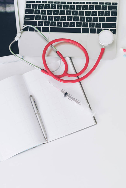 Medical healthcare backgrounds flat lay objects with copy space. Doctor stethoscope, medicine, laptop computer and notebook on white office table. - Фото, зображення
