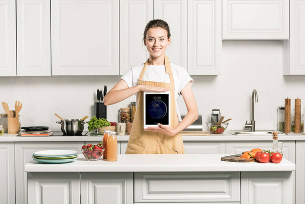 attractive girl holding ipad in kitchen and looking at camera - Φωτογραφία, εικόνα