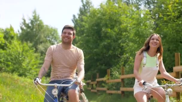 people, leisure and lifestyle concept - happy young friends riding fixed gear bicycles at country or summer park - Filmati, video