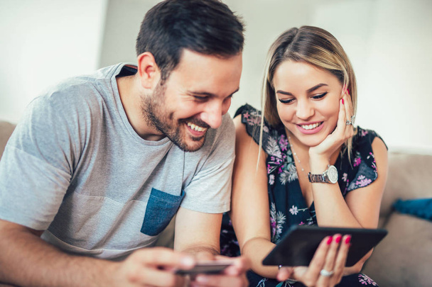 smiling happy couple with tablet pc and credit card shopping at home , technology and online shopping concept  - 写真・画像