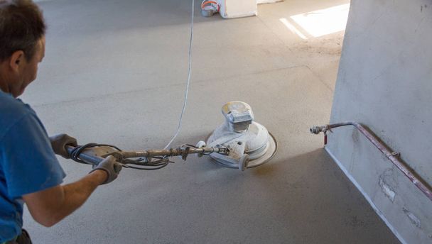 Laborer polishing sand and cement screed floor. - Photo, Image