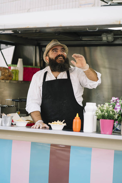Улыбающийся продавец продуктов питания с бородой в пищевой трюк
 - Фото, изображение