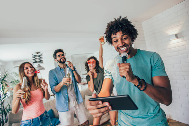 Grupo de amigos jugando karaoke en casa, Concepto de amistad y entretenimiento en casa
  - Foto, imagen