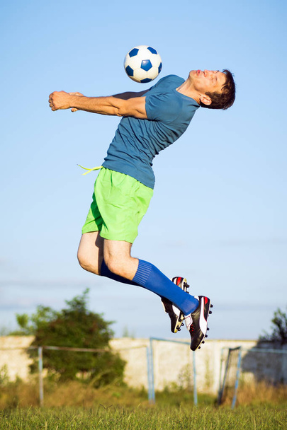 Спортивный момент прыжка футболиста с футбольным мячом в воздухе, действия на футбольном поле
. - Фото, изображение