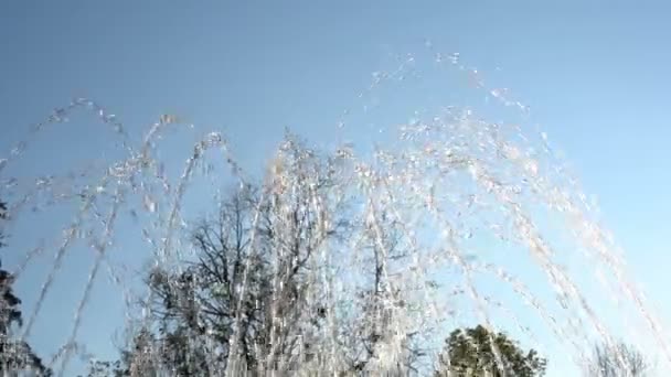Close-up van water jets. Waterstralen uit de fontein vliegen tegen de blauwe hemel in het stadspark. 4k, 25 fps. - Video