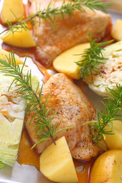 Vista verticale di cosce di pollo marinate, cunei di cavolo e patate pronte per andare in forno
 - Foto, immagini