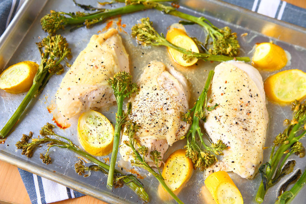 Overhead view of seasoned chicken breasts, broccolini and squash on a sheet pa - Photo, Image