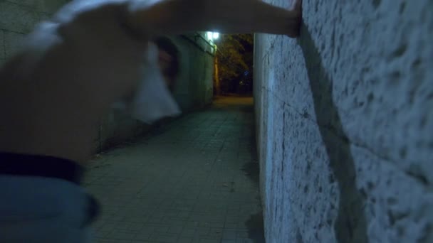 Een dronken man loopt alleen 's nachts via een voetgangerstunnel. 4k. - Video