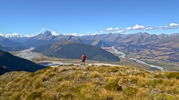 Aerial drone of young Caucasian adventure hiker with rucksack enjoying trekking in landscape of South Island New Zealand - Footage, Video
