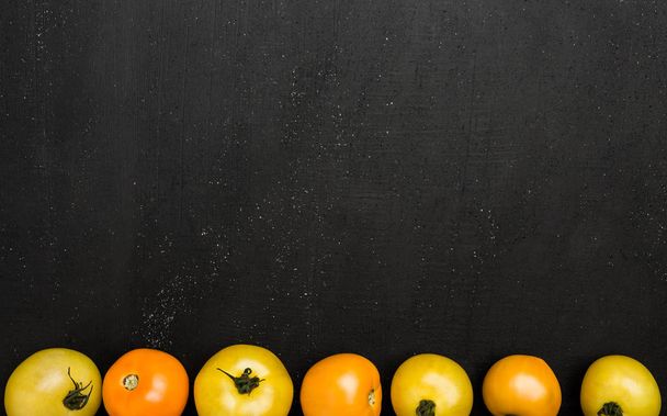 Line of yellow tomatoes, dark background with space for writing. Autumn vegetables, top view - Фото, изображение