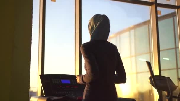 Young sporty muslim girl in hijab doing on the treadmill.Sunflare - Кадри, відео