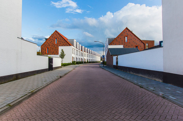 Perspectiva de rua com fachadas de novas pequenas casas, cidade de área residencial Oosterhout Holanda, Europa. Céu azul, bom tempo
 - Foto, Imagem