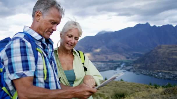 Zdravé kavkazských mužských a ženských senioři užívat výlet baví čtení mapu The Remarkables jezero Wakatipu Nového Zélandu  - Záběry, video