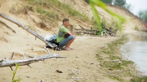Mature man on a sandy beach smokes vape - Footage, Video