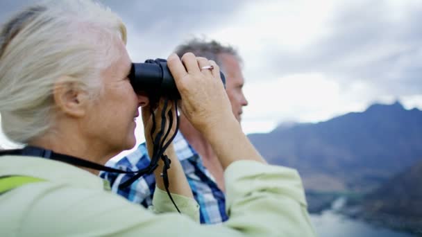 Feliz aposentado casal caucasiano com binóculos desfrutando de aposentadoria trekking natureza de The Remarkables Lake Wakatipu Nova Zelândia
  - Filmagem, Vídeo
