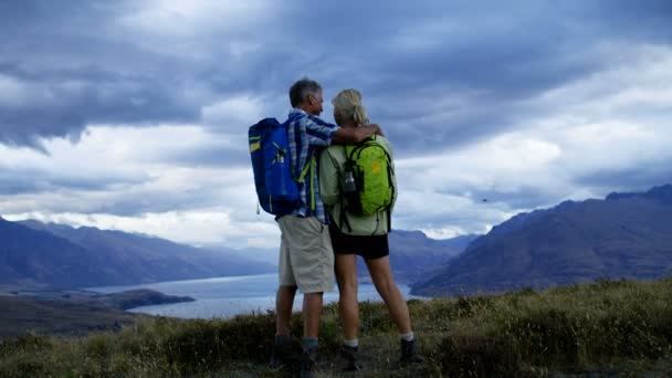 Szczęśliwy kaukaski męskich i żeńskich seniorów trekking korzystających emeryturę Mount Aspiring jezioro Wakatipu Nowa Zelandia  - Materiał filmowy, wideo