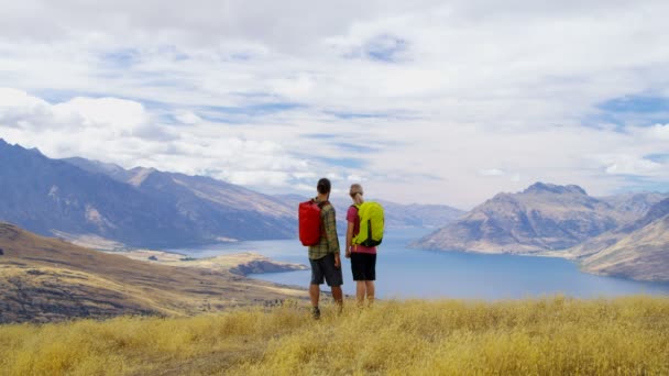 Young Caucasian adventure hikers with backpacks enjoying trekking in clean wilderness of Lake Wakatipu New Zealand  - Footage, Video