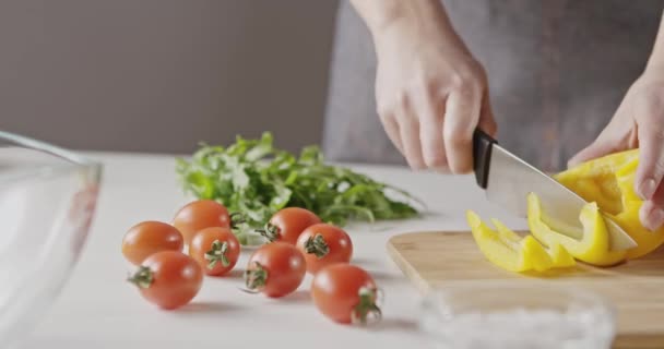 female hands cutting yellow paprika on wooden board - Filmmaterial, Video