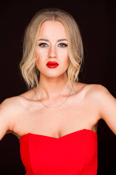 Portrait of beautiful young adult attractive sexy and sensuality blonde woman in red elegance fashionable dress isolated on dark background - Photo, image