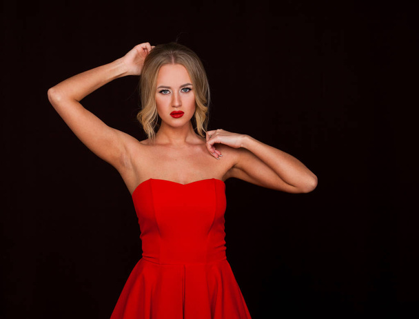 Portrait of beautiful young adult attractive sexy and sensuality blonde woman in red elegance fashionable dress isolated on dark background - Fotografie, Obrázek