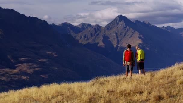 Actieve Kaukasische mannelijke en vrouwelijke reizigers buiten genieten van wandelen in de natuur van Fiordland The Remarkables Nieuw-Zeeland  - Video