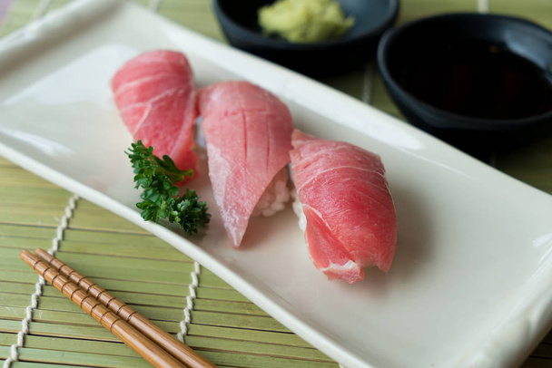 Otoro složka sushi na černý plát spolu s japonskou omáčkou a zelené listové dekorace, japonské jídlo, zblízka v sushi  - Fotografie, Obrázek