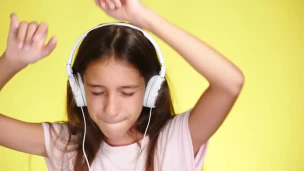 Teenage girl with headphones listening to music on color background. close-up, 4k, slow-motion. - Záběry, video