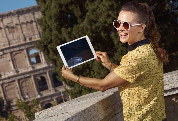 smiling tourist woman in yellow blouse taking photos with tablet PC near Colosseum , Rome, Italy - Foto, imagen