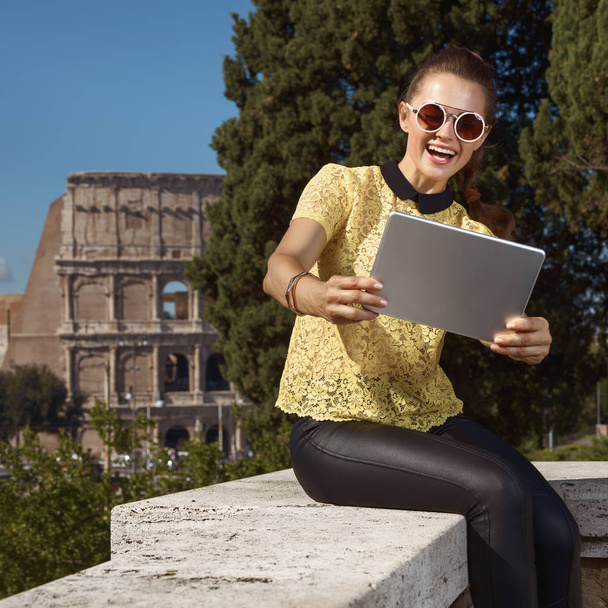 mujer turista de moda feliz en blusa amarilla tomando selfie con tableta PC cerca de Coliseo, Roma, Italia
  - Foto, imagen